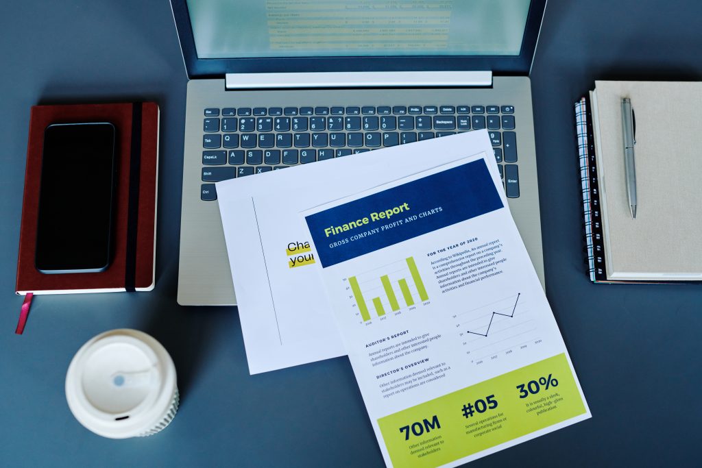 En trykt finansiel rapport ligger oven på en bærbar computer.